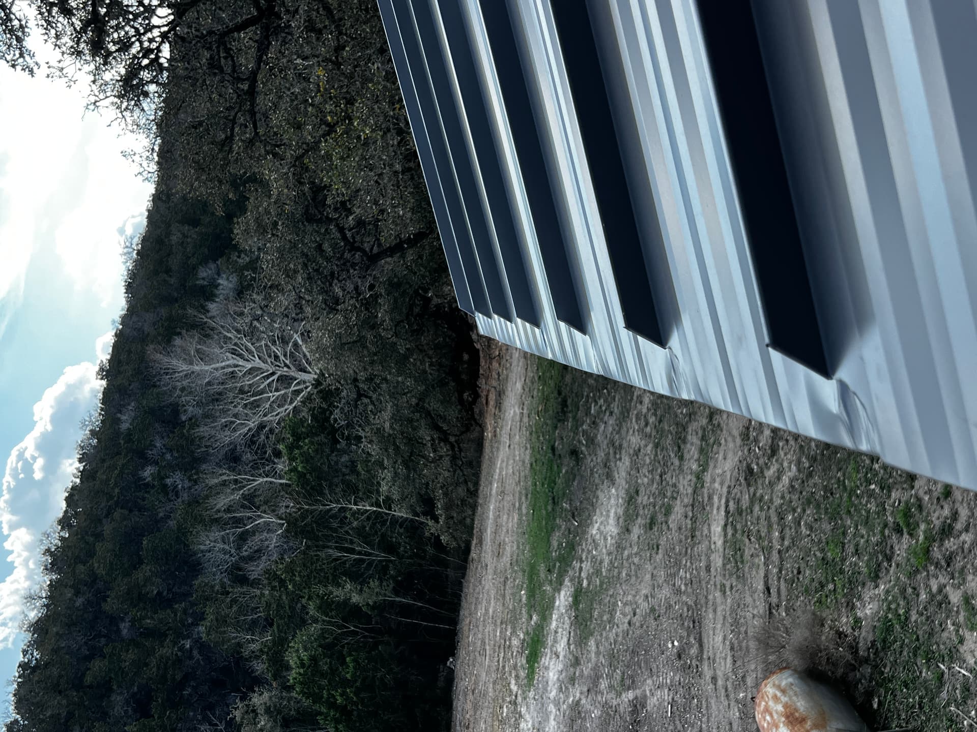 Metal roof edge with Hill Country oaks